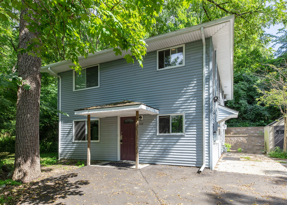 the front of a blue house with a red door     and trees